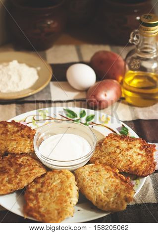 Traditional ukrainian food - deruny. Fried potato pancakes with sour cream on the check tablecloth