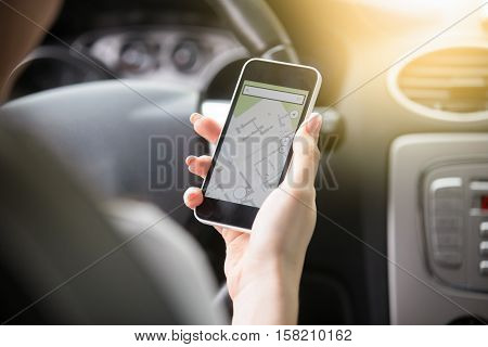 Close up of traveler female hand holding her phone with navigation system. Young woman traveling by car, trying to find the shortest route to a certain destination
