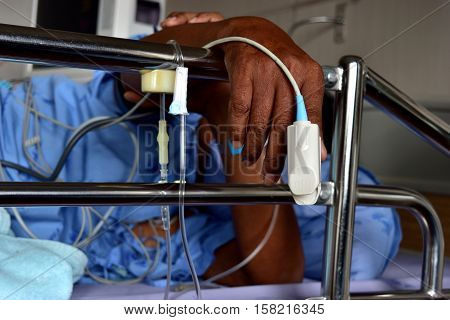 Asia 60 years old lying on a hospital bed saline iv drip and medical device.