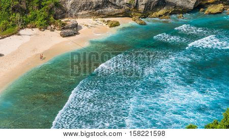 Couple on beautiful Atuh Beach with White Long Waves, Nusa Penida, Bali, Indonesia.