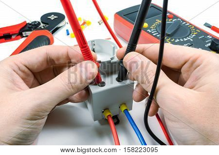 Measurement of voltage in electrical outlet with a multimeter on a white background