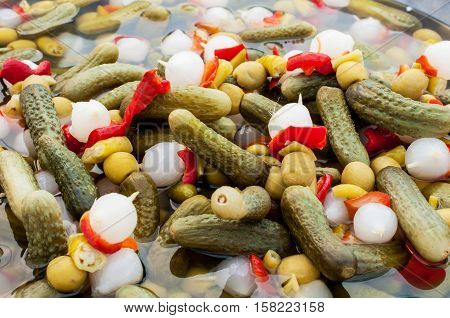 Close up view of mixed pickled vegetables cucumbers onion olives and peppers
