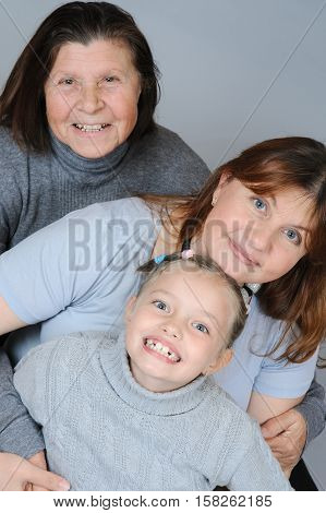 Child with her mother and grandmother embrace each other sitting on the floor.