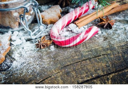 Christmas homemade gingerbreadcookies cinnamon anise and red candy cane on old wooden table with fir tree. Christmas treats concept. Christmas background. Selective focus. Copy space.