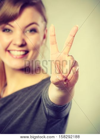 Celebration communication success concept. Cheerful lady makes v gesture. Young girl showing peace sign victory symbol.