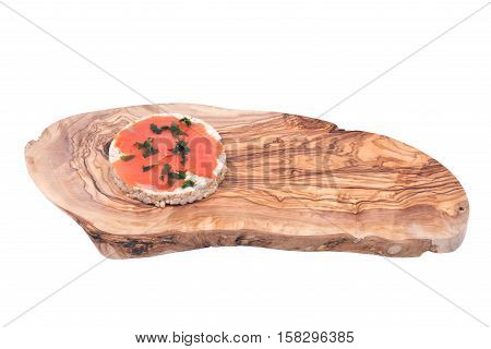 Smoked wild pacific sockeye salmon with parsley on organic brown rice cake and olive wood cutting board isolated on white background