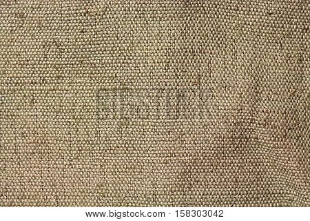 A piece of tarpaulin. The texture of coarse fabric with interwoven threads. Uneven surface. Close-up image for retro backgrounds or texturing.