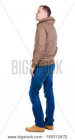 Back view of handsome man in brown windcheater looking up.   Standing young guy in jeans. Rear view people collection.  backside view of person.  Isolated over white background.