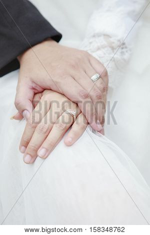 hand of groom and bride warming holding with wedding daimond ring
