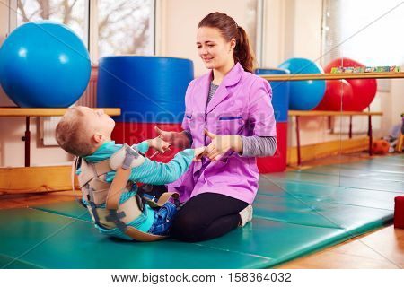 Cute Kid With Disability Has Musculoskeletal Therapy By Doing Exercises In Body Fixing Belts