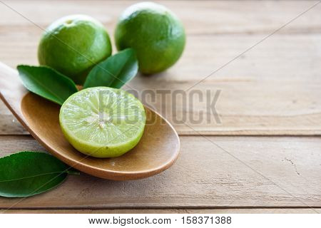 Lemons with green leaf in spoon on wooden background