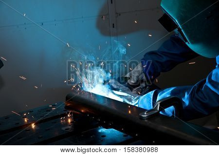 Welder working with electrode at semi-automatic arc welding.