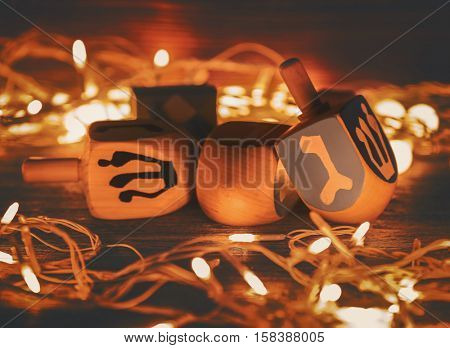 Composition of dreidels for Hanukkah and garland on wooden table