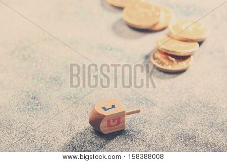 Wooden dreidel for Hanukkah on light sparkling background