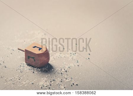 Wooden dreidel for Hanukkah on light background