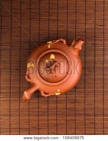 brown Chinese teapot of Yixing clay with traditional ornament on bamboo Mat
