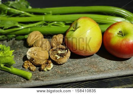 Ingredients for Waldorf salad - celery apples walnuts - fresh and healthy vegetables on granite board.