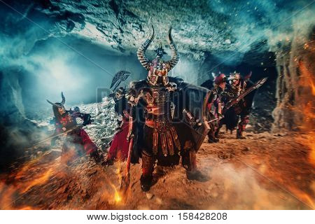 Battle of powerful knights in heavy armor in the Dungeon. Mighty warrior with the flaming axe on the foreground.