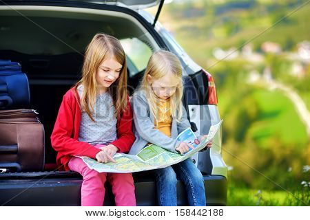 Two Adorable Little Sisters Exploring A Map Before Going On Vacations With Their Parents