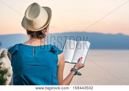 Woman Reading A Book With A Sunset View