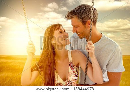 happy lovers swinging with sun behind
