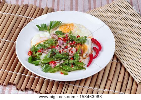 Spicy wing bean with minced pork topped fried egg as Yum Khai Doa in Thai.