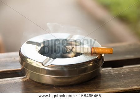 smoking a cigarette,  cigarette in hand, ashtray