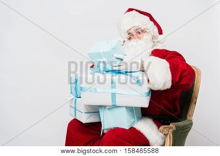 Photo of happy Santa Claus with giftboxes looking at them.