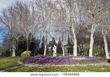 Flower bed at Retiro Park Madrid Spain. The statue depicts Hercules slaying Nemean lion.