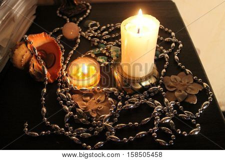 decoration for holiday night two bright burn candles, silver chaplet, flowers, crystals, shells