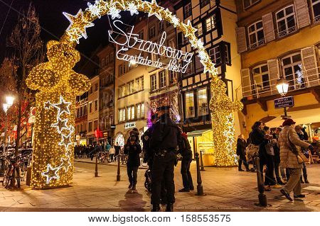 STRASBOURG FRANCE - NOV 28 2015: Police officers surveilling the entrance gate with neon Christmas decorations of the Christmas Market in Strasbourg with high grade security after Paris attacks