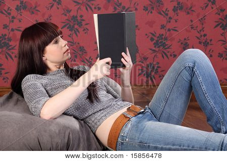 Kaunis nuori nainen makaa Bean Bag-oppikirja