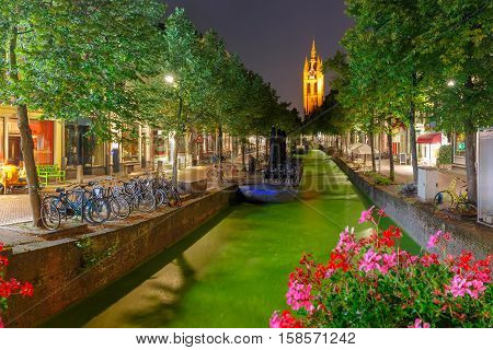 Oude Delft canal and leaning tower of Gothic Protestant Oude Kerk church at night, Delft, Holland, Netherlands