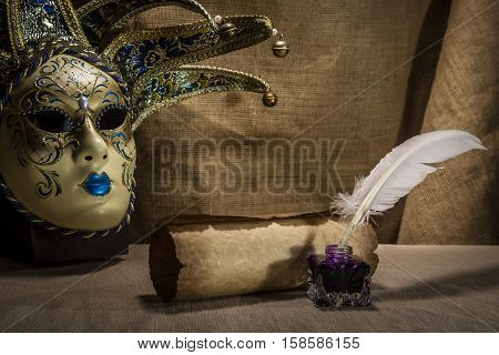 Literature concept. Old inkstand with feather near scroll and venezian mask on canvas background.