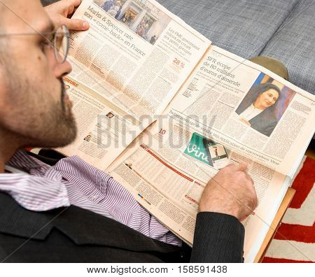 PARIS FRANCE - NOV 12 2016: Man reading Le Figaro French Economie newspaper - enjoying article about Twitter planning to sell Vine social network
