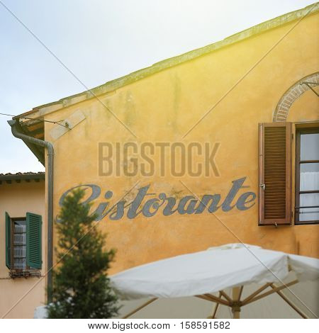Beautiful Italian Restaurant sign (Ristorante) on a building with typical Tusacany yellow color.