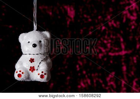 Hanging Christmas Teddy Bear On A Dark Red Background