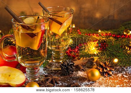 hot mulled apple cider with spices and christmas lights and decorations. christmas drink
