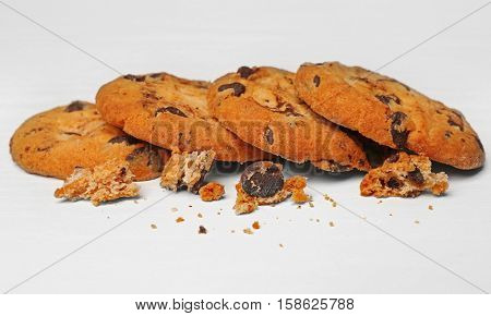 Tasty cookies with chocolate chips and crumbs on white background