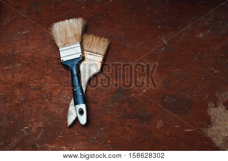 Two brushes lay on the table with a rough textured old