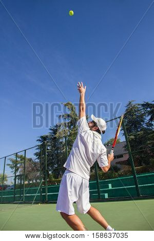 Professional tennis player is doing a kick tennis on a tennis court on a sunny summer morning. He is dressed in sportswear.