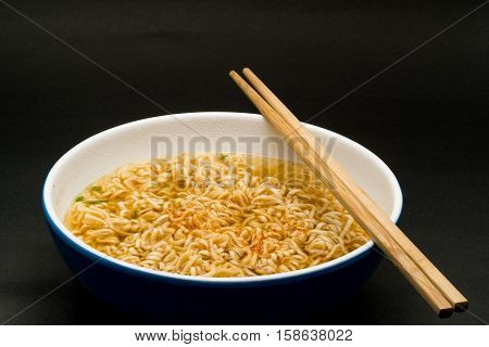 Cooked instant rice noodles in a bowl on dark background