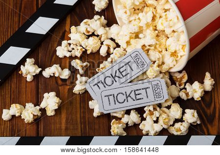 Clapper board, spilled popcorn and movie tickets on a background of boards