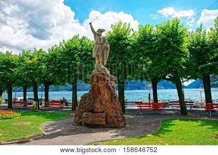 Lugano, Switzerland - August 25, 2013: Sculpture of William Tell at the promenade of the luxurious resort in Lugano on Lake Lugano and Alps mountains in Ticino canton of Switzerland.