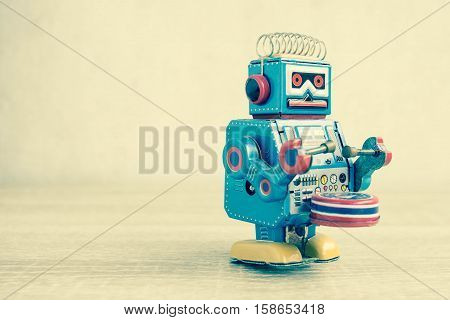 Old robot toy on wood table, vintage color style, vintage tone background.