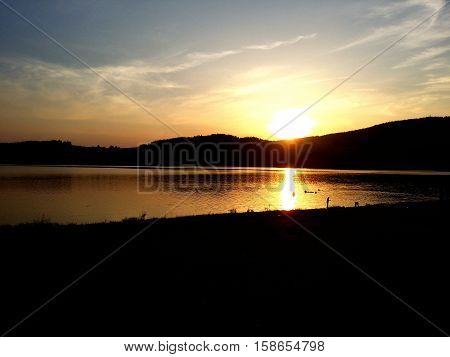 Sundown over the hills with reflections on the watter.
