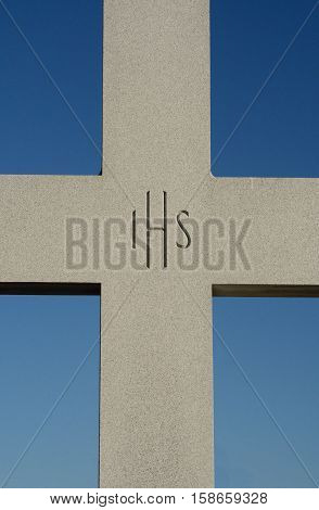 Granite cross with Chistogram IHS engraved in center against blue sky