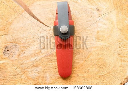 Tourist knife in a plastic case on a wooden background.