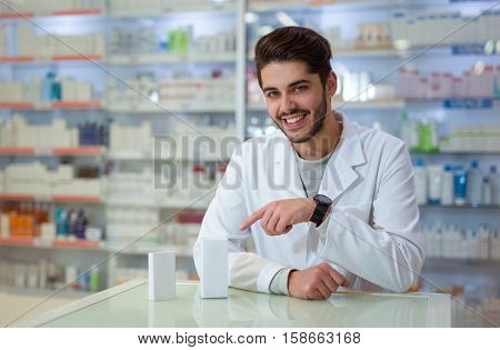 Friendly male pharmacist dispensing medicine holding a box of tablets