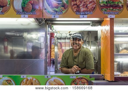 New York, United States of America - November 18, 2016: A happy street cart vendor looking out of his selling window